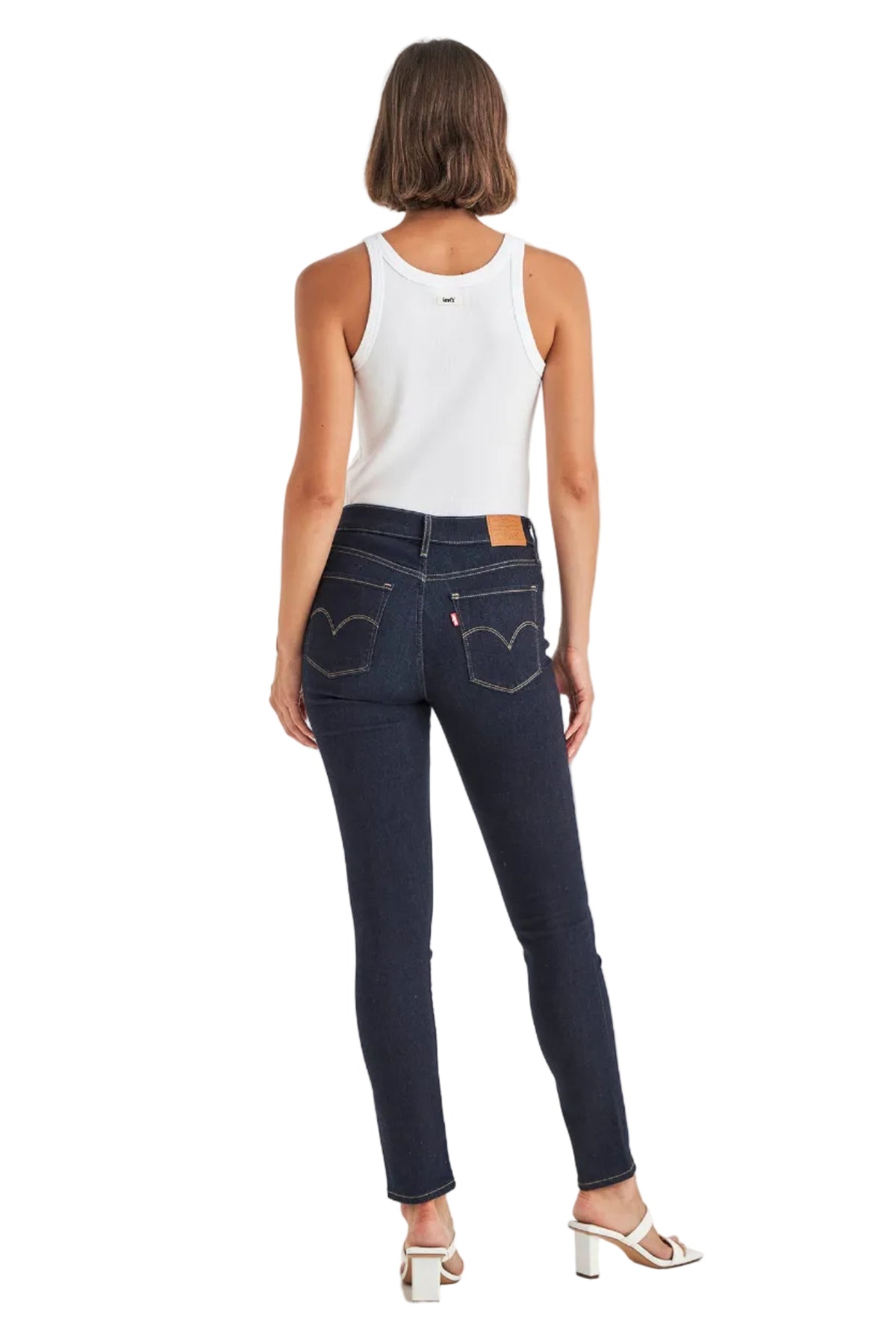Woman wearing dark blue jeans and a white tank top on a white background