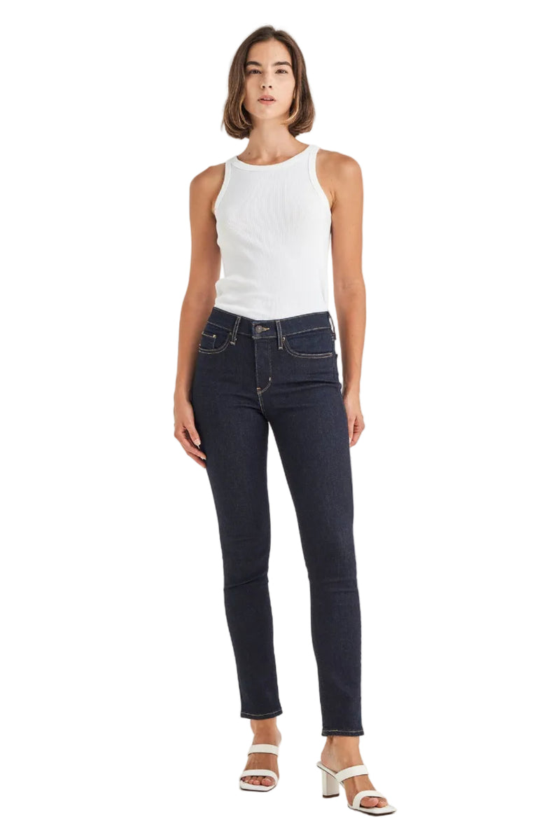 Woman wearing a white tank top and dark blue jeans on a white background