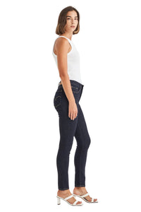 Woman wearing dark blue jeans and a white top on a light gray background