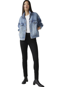 A woman standing, wearing Levi's 311 Shaping Skinny Jeans in a midnight gaze color, paired with a denim jacket and black shoes.