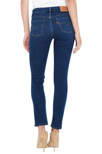 Rear view of a model wearing dark blue skinny jeans with beige high heels, shown against a plain white background.