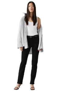 A woman standing, wearing Levi's 314 Shaping Straight Jeans in a midnight gaze color, paired with a white top and a gray cardigan.