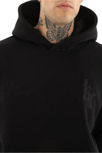 Person wearing a black hoodie with visible branding on a plain background