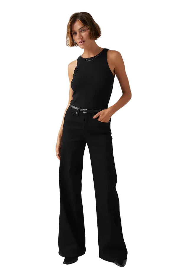 Woman wearing a black sleeveless top and black flared pants on a gray background