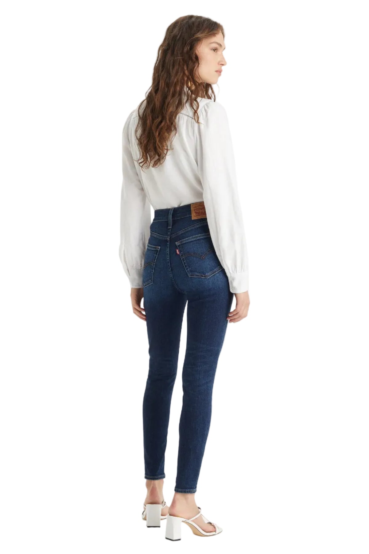 Woman wearing blue jeans and a white shirt on a white background