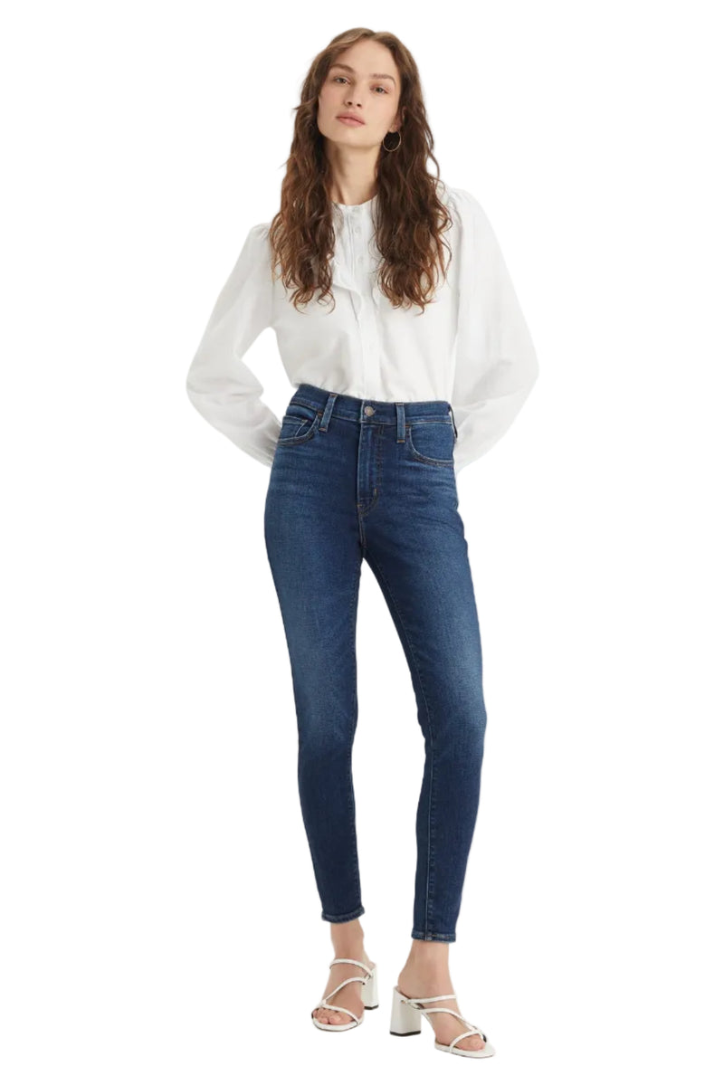 Woman wearing a white blouse and blue jeans on a white background