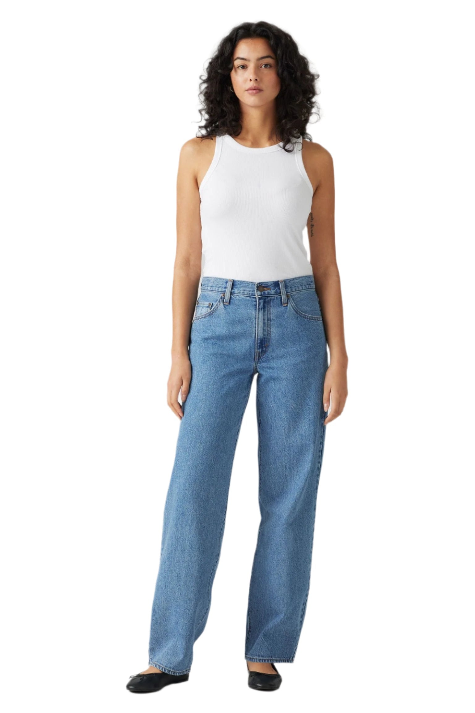 Woman wearing a white sleeveless top and blue jeans on a white background