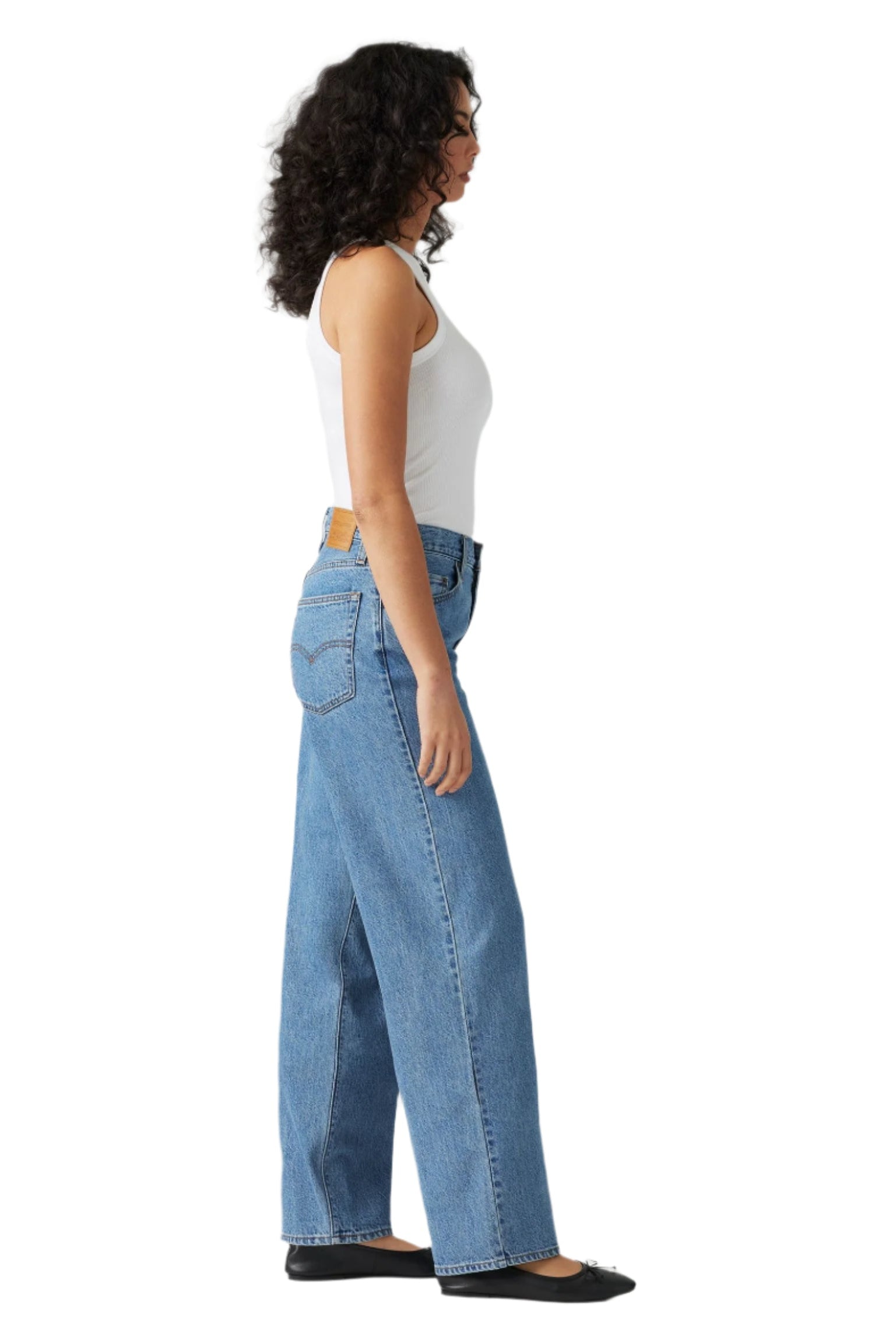 Person wearing blue jeans and a white top from the side.