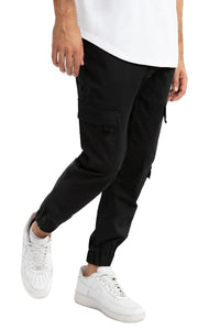 Person wearing black cargo pants and white sneakers on a light gray background