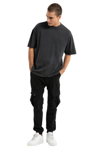 Man wearing a black t-shirt and black pants on a light gray background