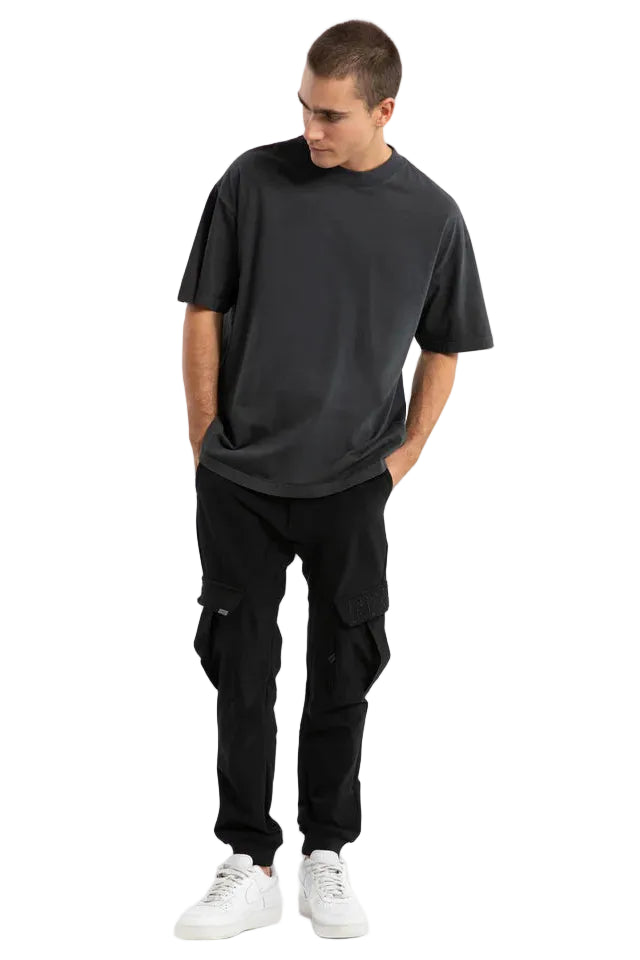 Man wearing a black t-shirt and black pants on a light gray background