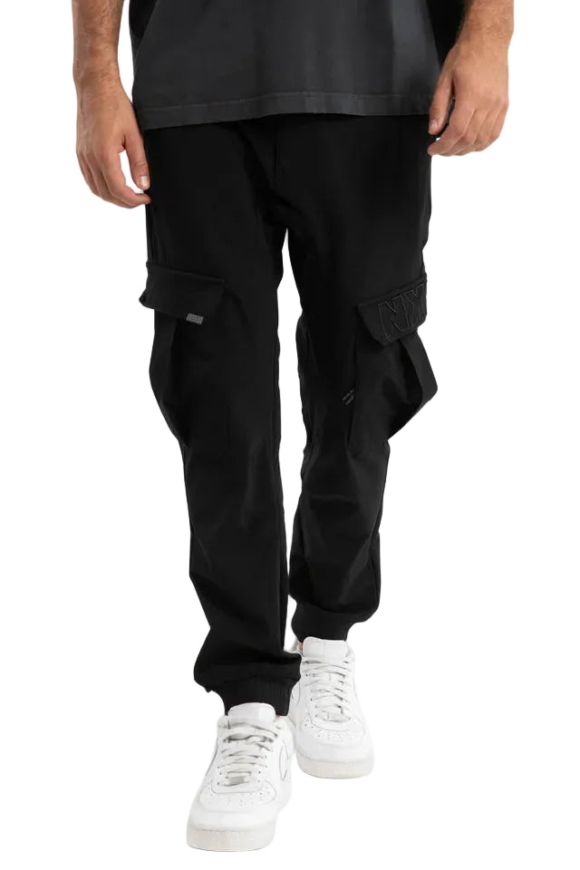 Person wearing black cargo pants and white sneakers on a light gray background