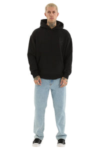 Person wearing a black hoodie and light blue jeans on a white background