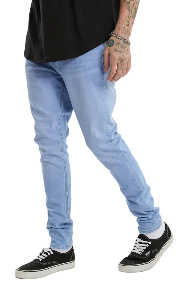 Person wearing light blue jeans and black sneakers on a white background