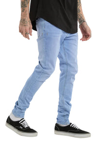Person wearing light blue jeans and black sneakers on a white background
