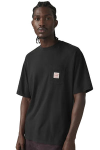 Man wearing a black t-shirt with a small logo on a plain background