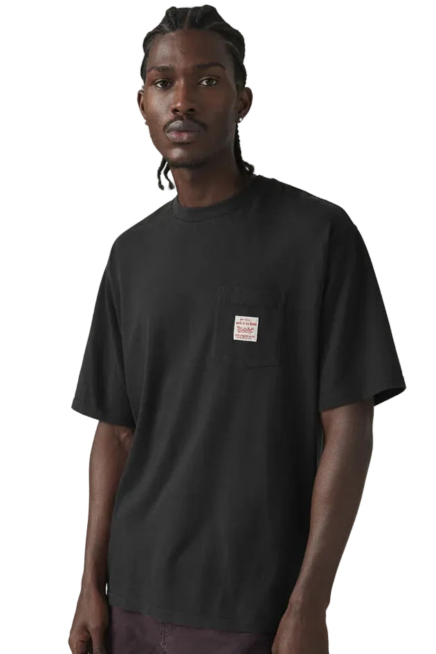 Man wearing a black t-shirt with a small logo on a plain background
