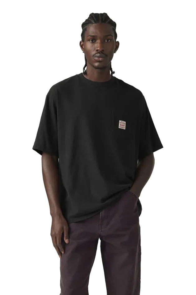 Person wearing a black t-shirt with a small logo on a plain background