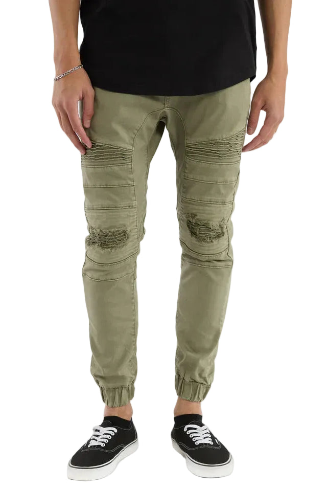 Person wearing green distressed jogger pants on a white background