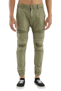 Olive green distressed jogger pants worn by a person on a white background