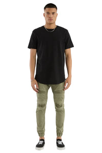 Man wearing a black t-shirt and green distressed jeans on a white background