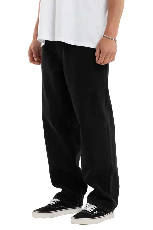 Person wearing black pants and white sneakers on a plain background