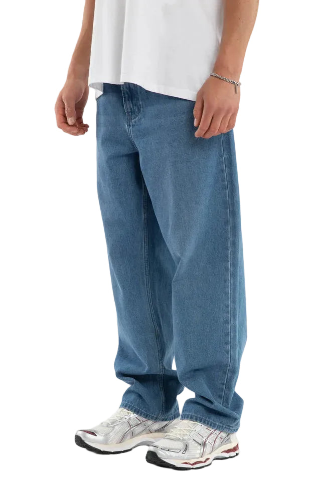 Person wearing blue jeans and a white shirt on a plain background