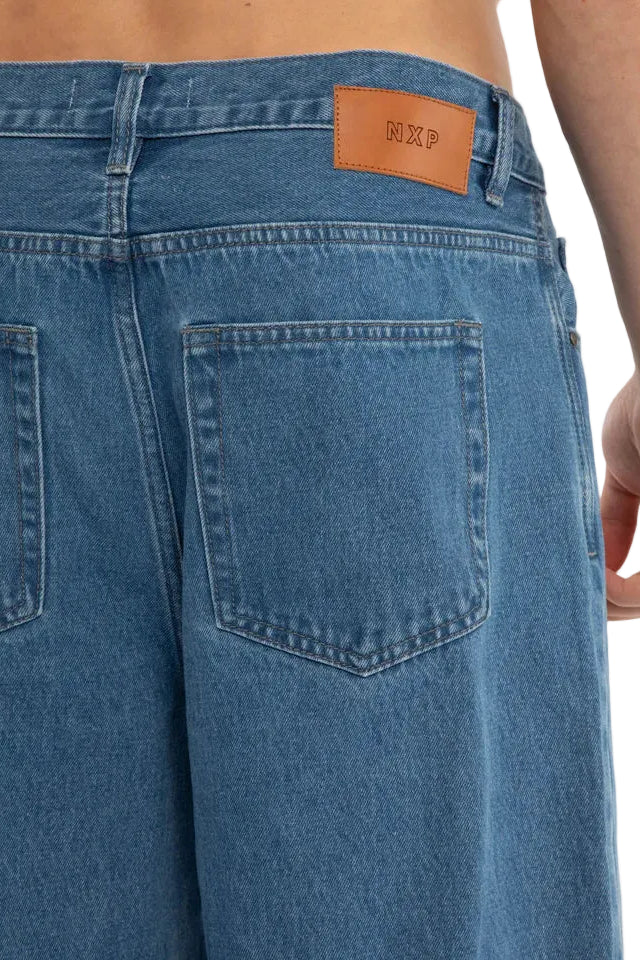 Blue jeans with a brand label on the back pocket against a white background