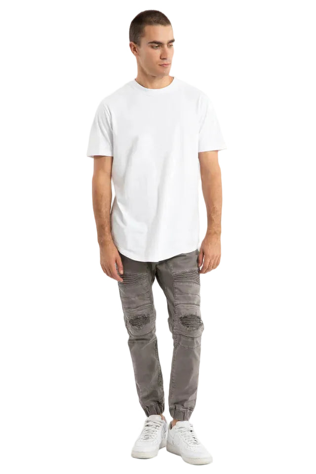 Man wearing a white t-shirt and gray pants on a plain background
