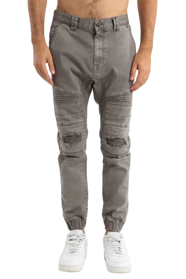 Person wearing gray distressed jogger pants on a white background