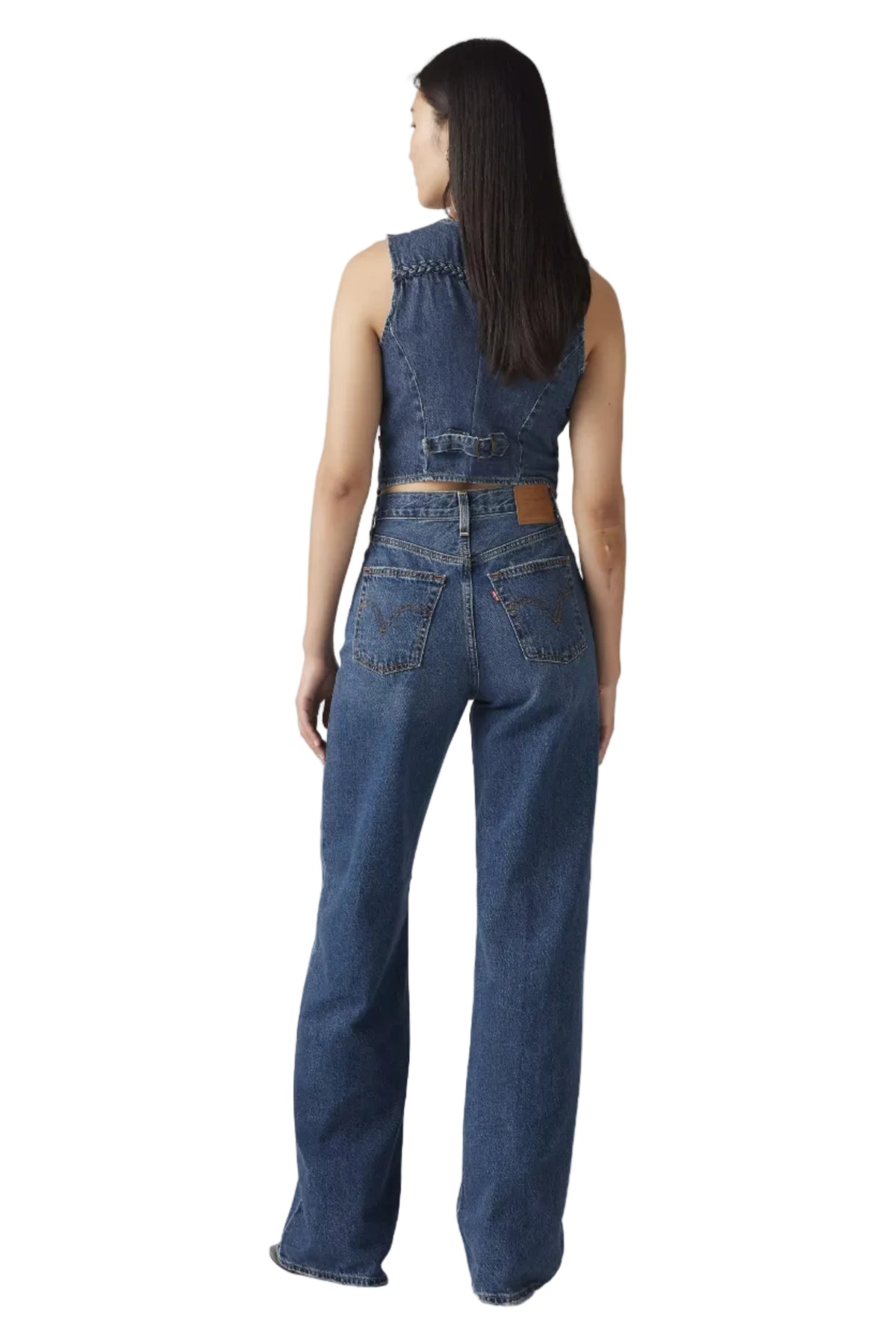 Woman wearing a denim jumpsuit on a plain background
