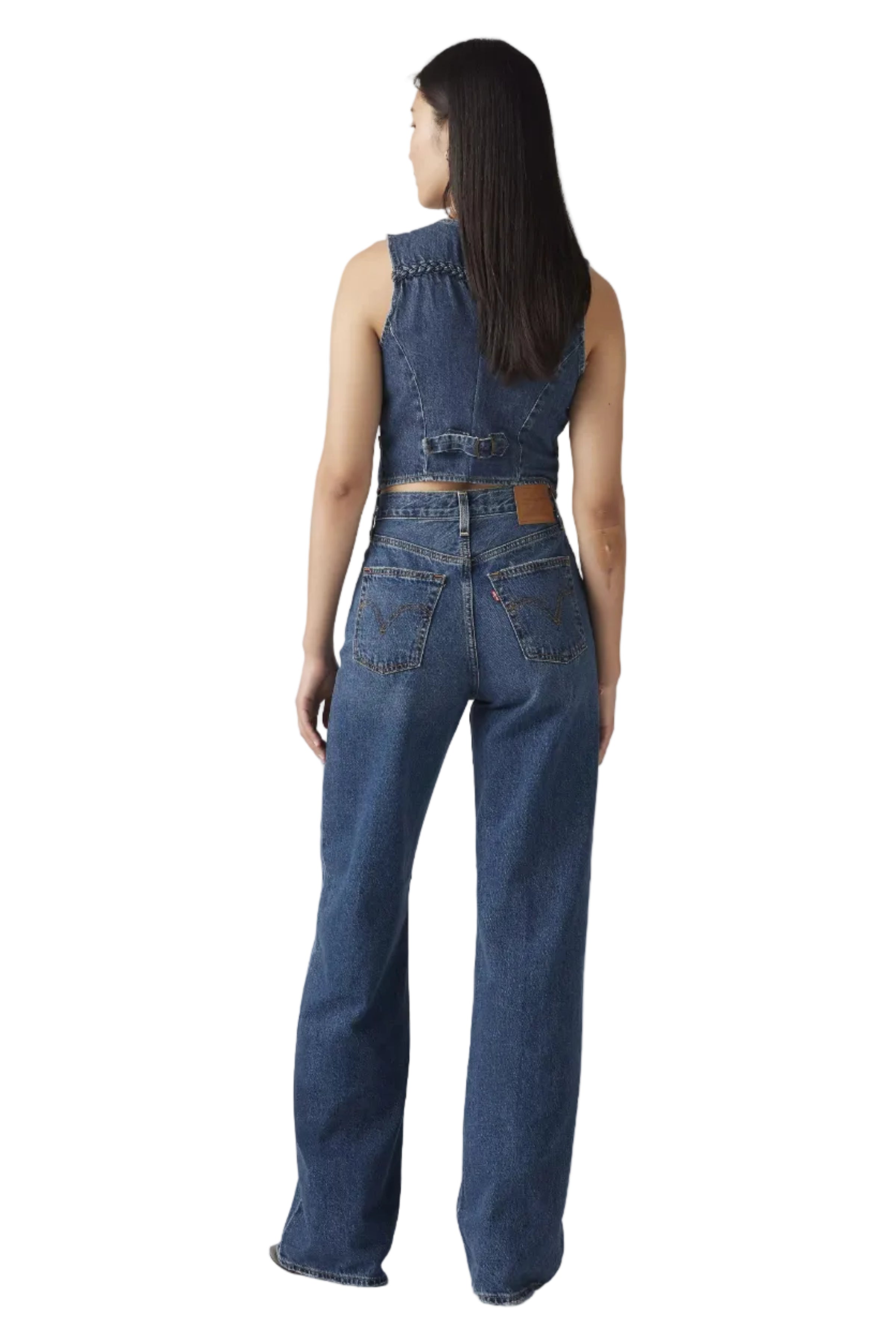 Woman wearing a denim jumpsuit on a plain background