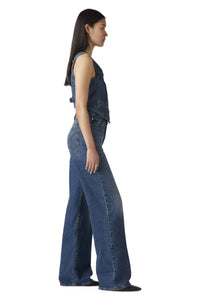 Woman wearing a sleeveless denim jumpsuit on a white background