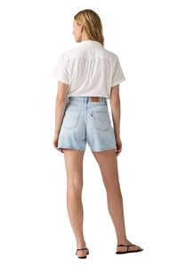 Person wearing light blue denim shorts and a white shirt on a plain background