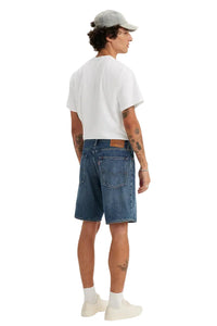Person wearing a white t-shirt, blue denim shorts, and a gray cap on a white background