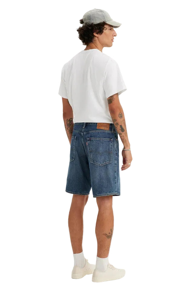Person wearing a white t-shirt, blue denim shorts, and a gray cap on a white background