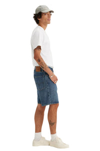 Person wearing a white t-shirt, blue denim shorts, and a cap on a white background