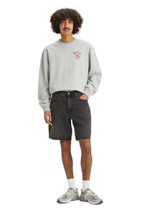Person wearing a gray sweatshirt and black shorts on a white background