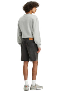 Person wearing a gray sweatshirt and black shorts on a white background