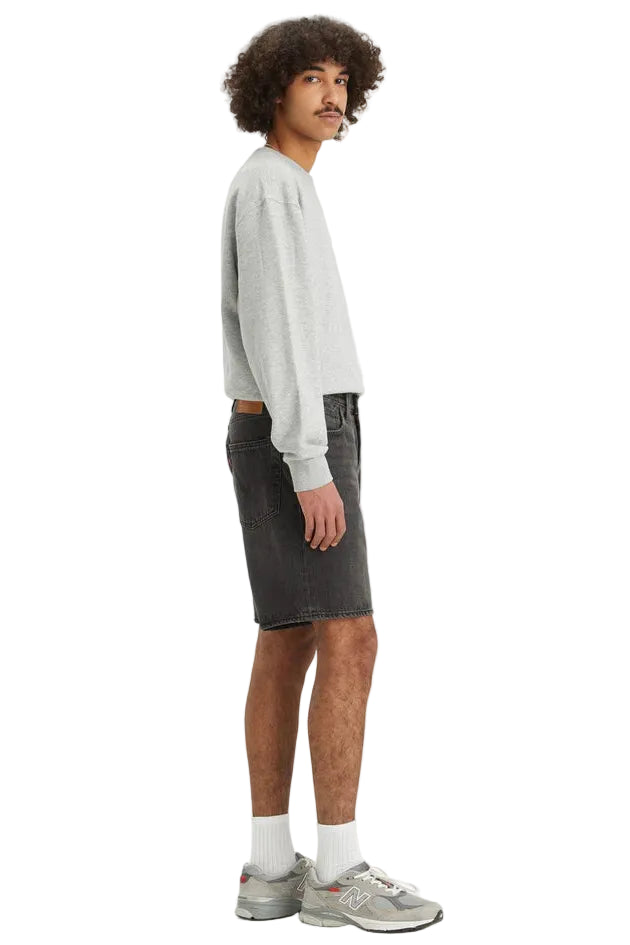 Man wearing a light gray sweatshirt and dark shorts on a white background