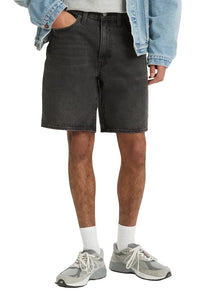 Person wearing black denim shorts, gray sneakers, and a light blue jacket on a white background