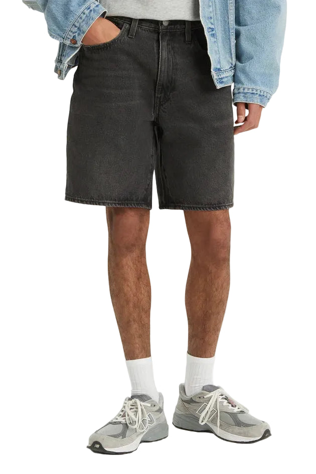 Person wearing black denim shorts, gray sneakers, and a light blue jacket on a white background