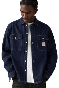 Man wearing a dark blue denim jacket on a plain background