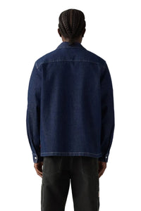 Person wearing a blue denim jacket on a plain background