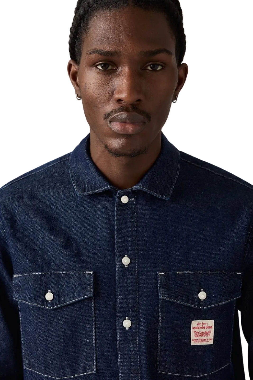 Man wearing a dark blue denim shirt with a visible brand patch on a plain background