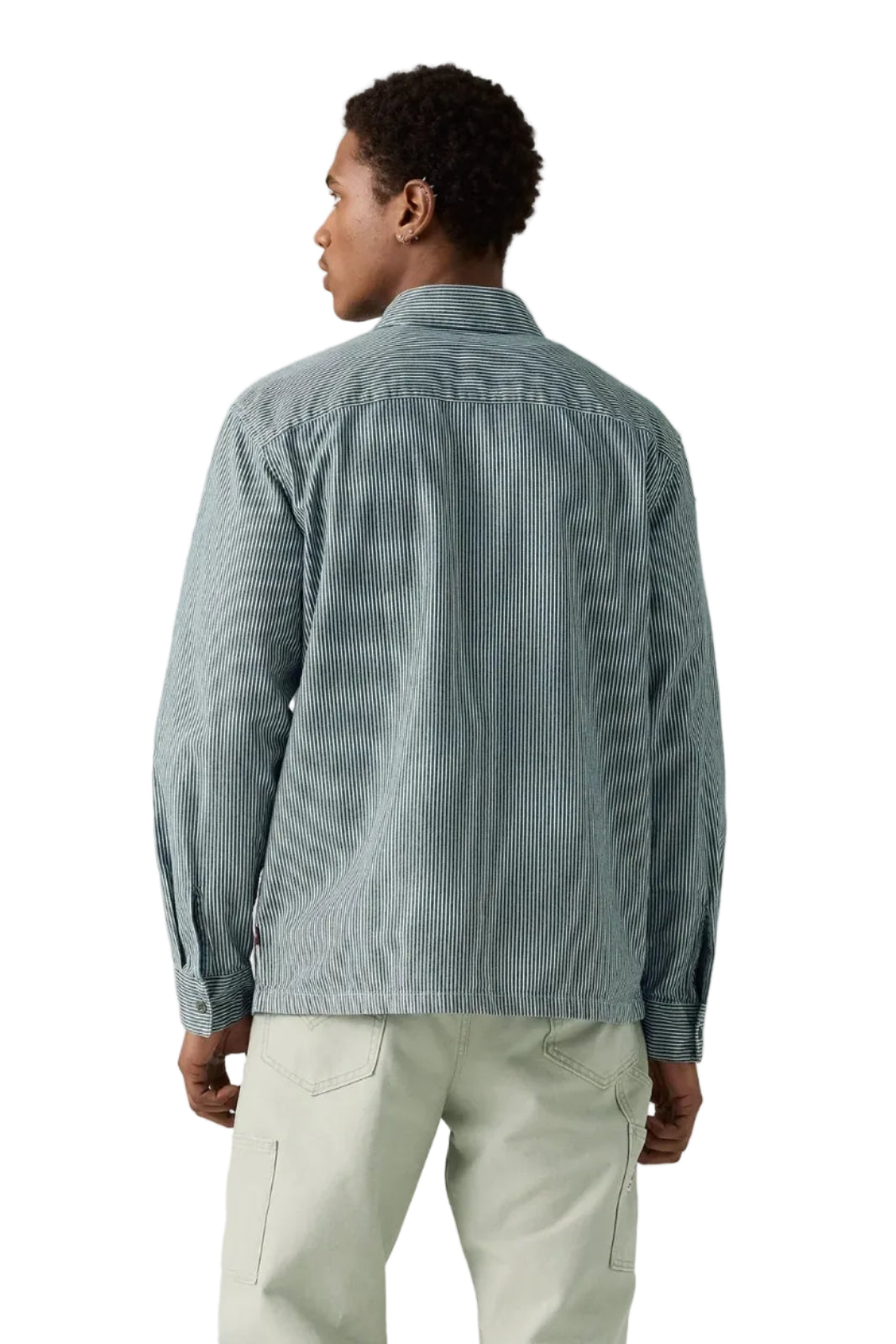 Person wearing a light blue corduroy shirt and light green pants on a plain background