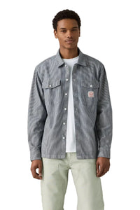 Man wearing a gray checkered shirt over a white t-shirt on a plain background