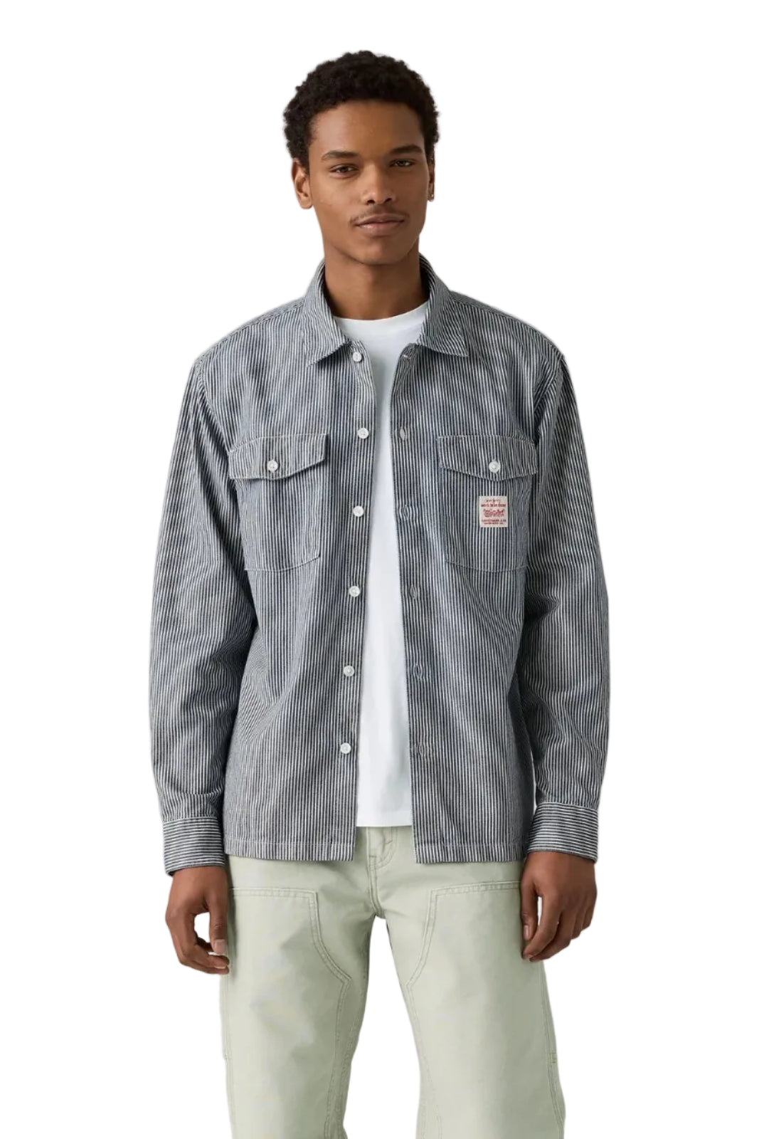 Man wearing a gray checkered shirt over a white t-shirt on a plain background