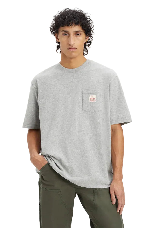 Person wearing a gray t-shirt with a small logo on a plain background