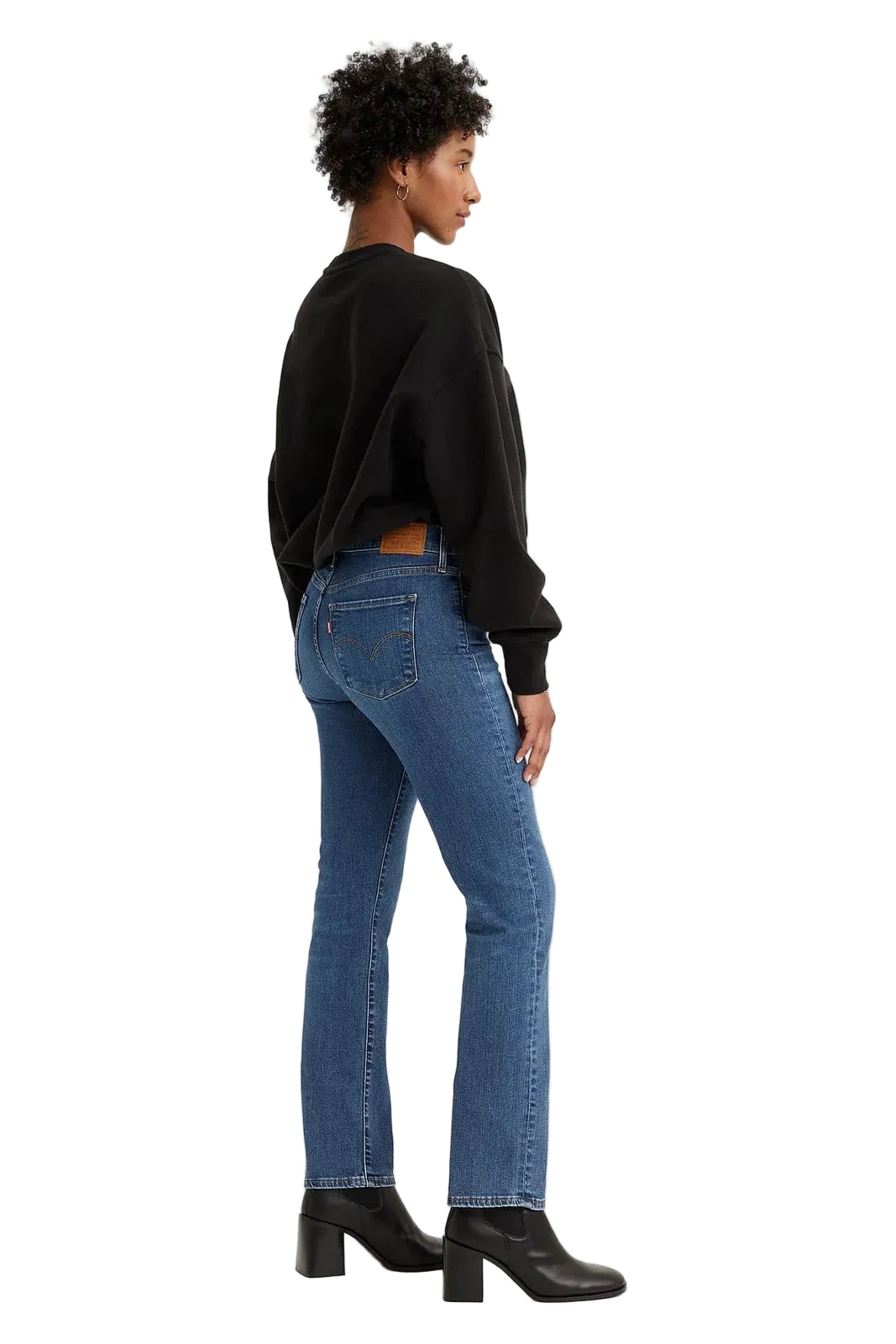 Woman wearing blue jeans and a black sweater on a white background